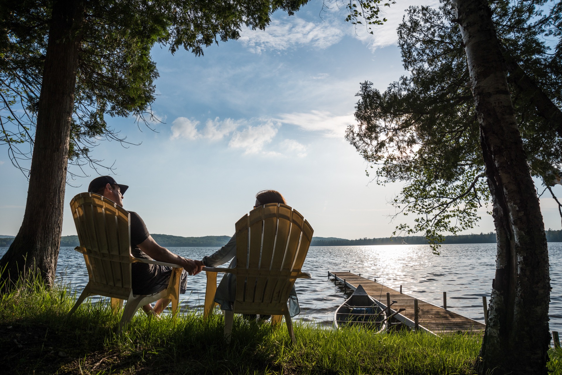 Two people relaxing in striped chairs beside a lake